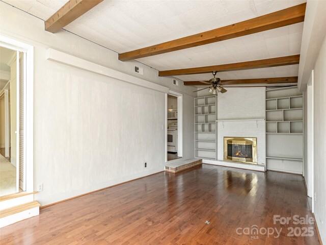 34 Lockhart Rd, Tryon, NC 28782 - unfurnished living room featuring ceiling fan, wood finished floors, beam ceiling, a brick fireplace, and built in shelves