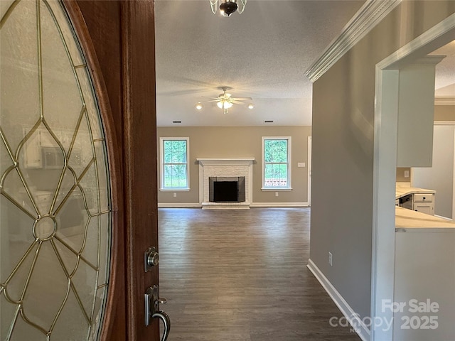 4402 Poxon Ln, Monroe, NC 28110 - unfurnished living room with a ceiling fan, dark wood-type flooring, a textured ceiling, a fireplace, and crown molding