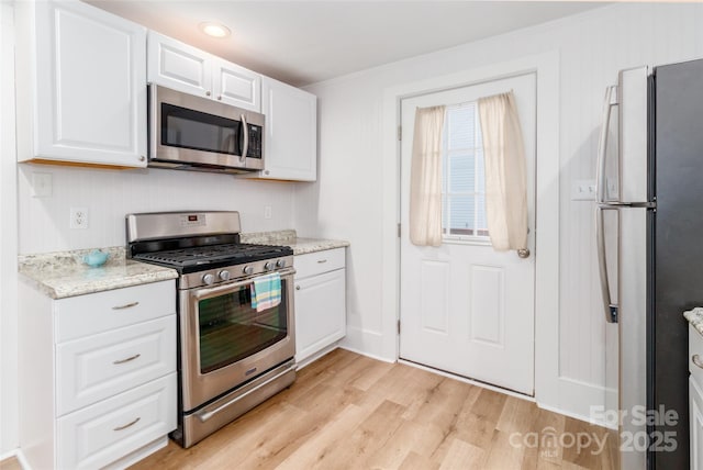 13414 Central Ave, Huntersville, NC 28078 - kitchen with appliances with stainless steel finishes, light wood-type flooring, white cabinets, ornamental molding, and light stone counters
