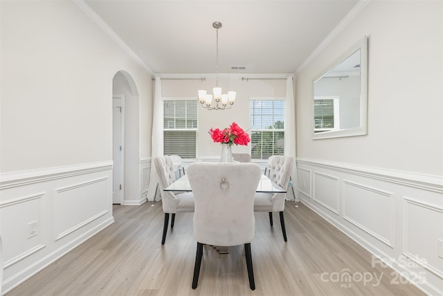 205 Falls Cove Dr, Troutman, NC 28166 - dining area with crown molding, a chandelier, light wood finished floors, a decorative wall, and arched walkways