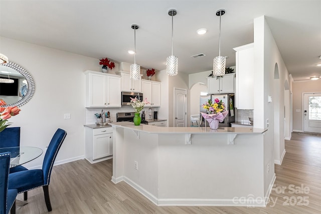 205 Falls Cove Dr, Troutman, NC 28166 - kitchen with stainless steel appliances, arched walkways, decorative backsplash, light wood-style floors, and recessed lighting