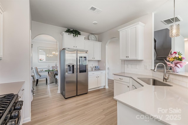 205 Falls Cove Dr, Troutman, NC 28166 - kitchen featuring stainless steel refrigerator with ice dispenser, arched walkways, gas range oven, light wood-style floors, and tasteful backsplash