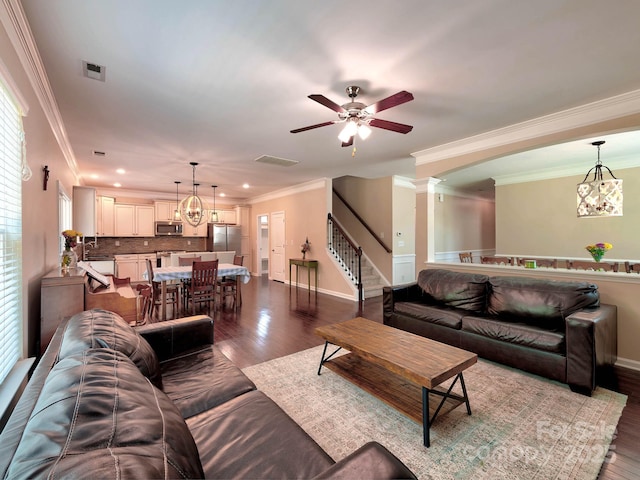 5797 Mcclintock Dr, Denver, NC 28037 - living room featuring ornamental molding, a ceiling fan, a chandelier, dark wood-style floors, and stairs
