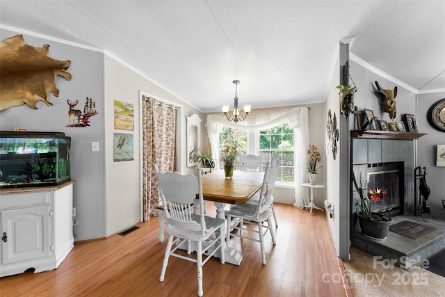 5425 Creek Run Ct, Kings Mountain, NC 28086 - dining room with vaulted ceiling, a chandelier, light wood-type flooring, ornamental molding, and a tile fireplace