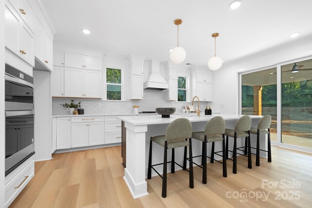 4032 Brandy Creek Ct, Clover, SC 29710 - kitchen with custom range hood, stainless steel double oven, tasteful backsplash, light countertops, and light wood finished floors