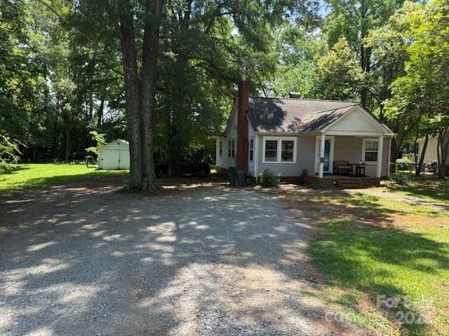 917 Tennyson Dr, Charlotte, NC 28208 - view of front of home featuring a porch, a storage unit, gravel driveway, and view of scattered trees