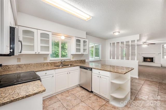 7008 Wannamaker Ln, Charlotte, NC 28226 - kitchen with appliances with stainless steel finishes, a peninsula, a textured ceiling, white cabinets, and a brick fireplace