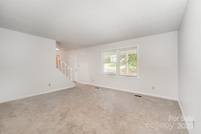 7008 Wannamaker Ln, Charlotte, NC 28226 - empty room featuring a textured ceiling, stairs, and carpet flooring