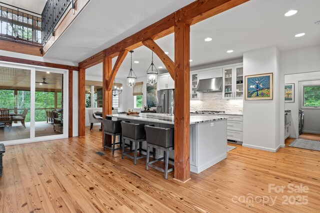 891 Crescent Trl Unit 273, Highlands, NC 28741 - kitchen with ventilation hood, light wood finished floors, white cabinetry, a kitchen breakfast bar, and stainless steel appliances