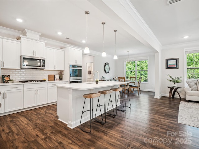 1008 Millbridge Pkwy, Waxhaw, NC 28173 - kitchen featuring appliances with stainless steel finishes, crown molding, an island with sink, dark wood-style flooring, and a kitchen breakfast bar