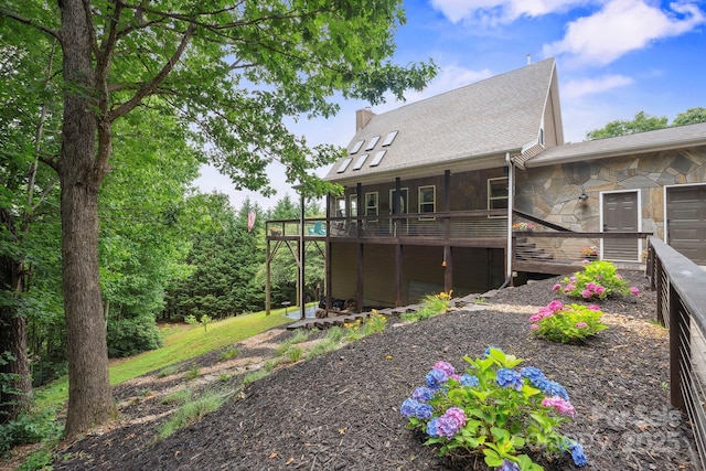 3381 Stones Throw Dr, Valdese, NC 28690 - back of house with stone siding, a deck, a shingled roof, and a chimney