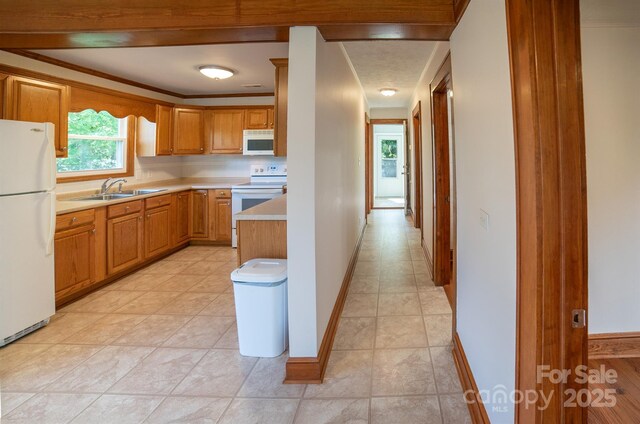 4879 Denton Chapel Rd, Morganton, NC 28655 - kitchen with white appliances, light countertops, brown cabinets, light tile patterned floors, and ornamental molding