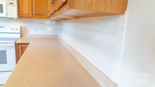 4879 Denton Chapel Rd, Morganton, NC 28655 - kitchen with white appliances, brown cabinets, light countertops, and decorative backsplash
