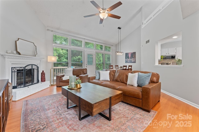 10043 Elsenham Ln, Charlotte, NC 28269 - living area featuring a ceiling fan, light wood-type flooring, a fireplace, and high vaulted ceiling