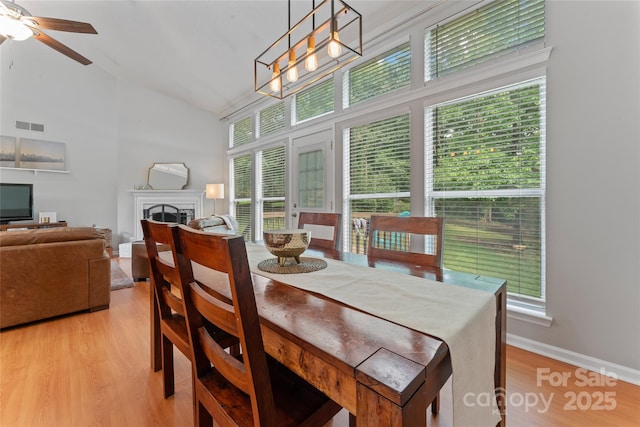 10043 Elsenham Ln, Charlotte, NC 28269 - dining space with healthy amount of natural light, light wood-type flooring, a fireplace, a ceiling fan, and high vaulted ceiling