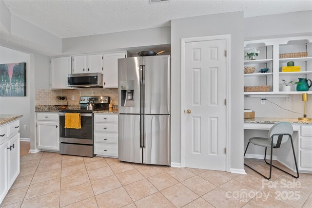 10043 Elsenham Ln, Charlotte, NC 28269 - kitchen with appliances with stainless steel finishes, white cabinetry, backsplash, light stone countertops, and light tile patterned floors