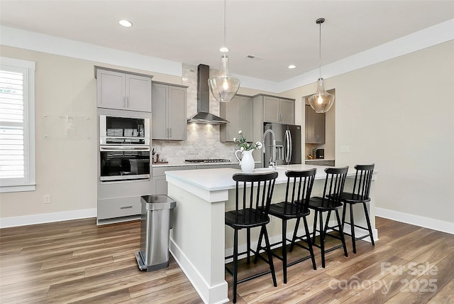5129 Whitman Ave, Matthews, NC 28105 - kitchen with stainless steel appliances, wall chimney exhaust hood, gray cabinetry, a kitchen island with sink, and light countertops