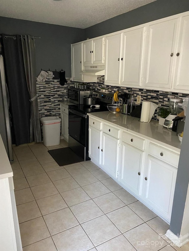 7401 Merrily Ln, Charlotte, NC 28214 - kitchen with electric stove, under cabinet range hood, white cabinets, light tile patterned floors, and a textured ceiling