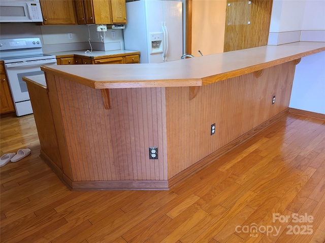 110 Kimberly Ln, Kings Mountain, NC 28086 - kitchen featuring white appliances, light wood-type flooring, light countertops, a kitchen breakfast bar, and a peninsula