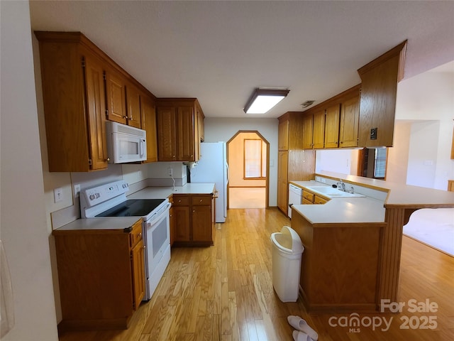 110 Kimberly Ln, Kings Mountain, NC 28086 - kitchen with white appliances, light wood finished floors, light countertops, a peninsula, and brown cabinets