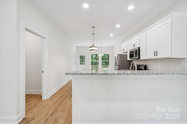 54 Reed St NE, Concord, NC 28025 - kitchen with stainless steel appliances, light stone countertops, light wood-type flooring, white cabinetry, and recessed lighting