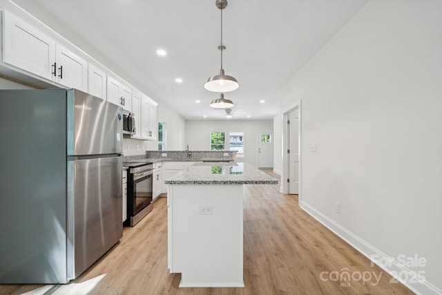 54 Reed St NE, Concord, NC 28025 - kitchen with appliances with stainless steel finishes, white cabinetry, light wood-type flooring, a center island, and a peninsula