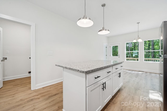 54 Reed St NE, Concord, NC 28025 - kitchen featuring light wood-style flooring, light stone counters, white cabinetry, pendant lighting, and a kitchen island