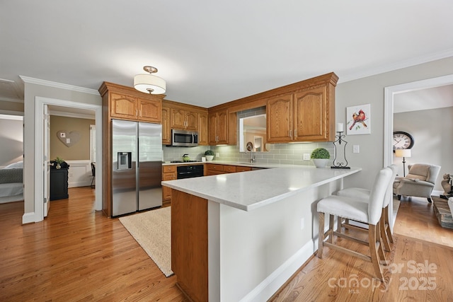 4824 Waxhaw Farms Rd, Waxhaw, NC 28173 - kitchen featuring stainless steel appliances, a peninsula, light wood finished floors, crown molding, and a breakfast bar area