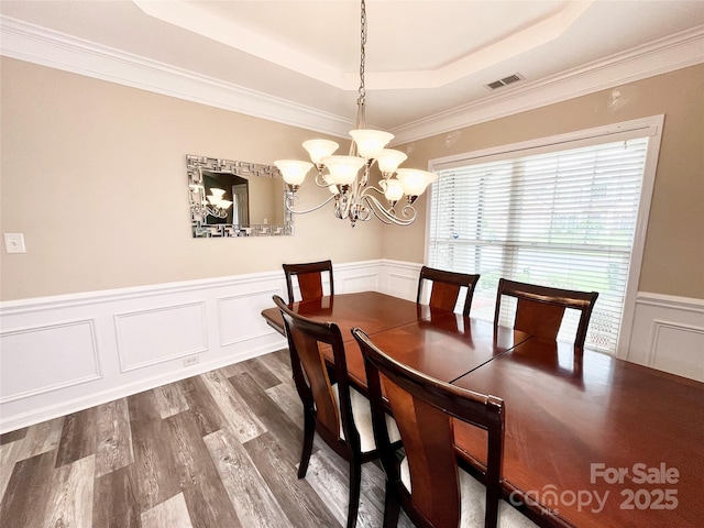 9792 Ravenscroft Ln NW, Concord, NC 28027 - dining area with a tray ceiling, dark wood finished floors, a chandelier, wainscoting, and a decorative wall