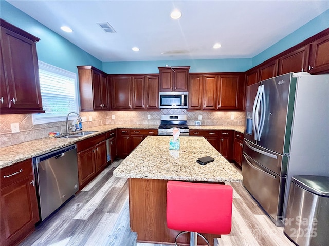 9792 Ravenscroft Ln NW, Concord, NC 28027 - kitchen featuring stainless steel appliances, light wood-type flooring, a center island, light stone counters, and tasteful backsplash