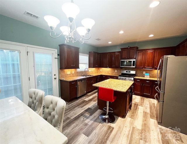 9792 Ravenscroft Ln NW, Concord, NC 28027 - kitchen featuring stainless steel appliances, a center island, a chandelier, a kitchen bar, and light wood-style floors