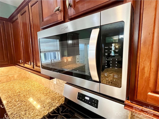 9792 Ravenscroft Ln NW, Concord, NC 28027 - kitchen with stainless steel appliances, decorative backsplash, and light stone countertops