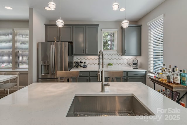2969 Simpson Dr, Charlotte, NC 28205 - kitchen with stainless steel refrigerator with ice dispenser, tasteful backsplash, hanging light fixtures, gray cabinetry, and light stone counters