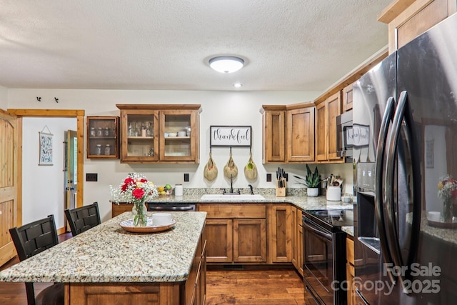 2171 Black Rock Rd, Cherokee, NC 28719 - kitchen with black appliances, brown cabinets, dark wood-style flooring, light stone countertops, and a textured ceiling