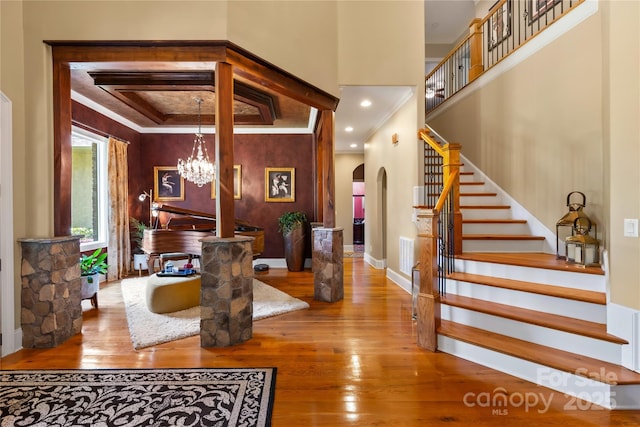 168 Blue Ridge Trl, Mooresville, NC 28117 - entrance foyer featuring arched walkways, wood-type flooring, a chandelier, ornamental molding, and stairs