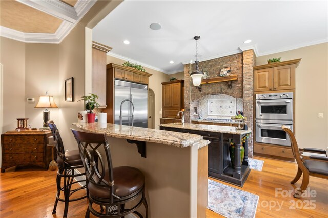 168 Blue Ridge Trl, Mooresville, NC 28117 - kitchen featuring appliances with stainless steel finishes, a peninsula, a breakfast bar area, light wood-type flooring, and a center island