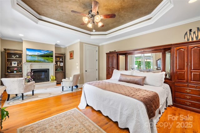 168 Blue Ridge Trl, Mooresville, NC 28117 - bedroom with a raised ceiling, light wood-style flooring, ornamental molding, a glass covered fireplace, and recessed lighting