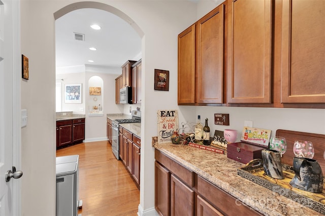1636 Ridge Haven Rd, Waxhaw, NC 28173 - kitchen with stainless steel appliances, arched walkways, light wood finished floors, light stone counters, and brown cabinets