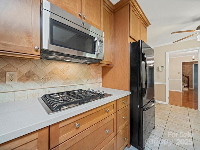 2020 Dawnshire Dr, Gastonia, NC 28054 - kitchen with stainless steel appliances, a ceiling fan, backsplash, brown cabinetry, and crown molding