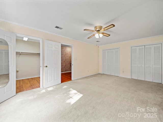 2020 Dawnshire Dr, Gastonia, NC 28054 - unfurnished bedroom featuring carpet, a ceiling fan, two closets, crown molding, and a walk in closet