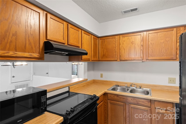 1604 Sharon Rd W Unit 30, Charlotte, NC 28210 - kitchen with under cabinet range hood, black appliances, light countertops, a textured ceiling, and brown cabinetry