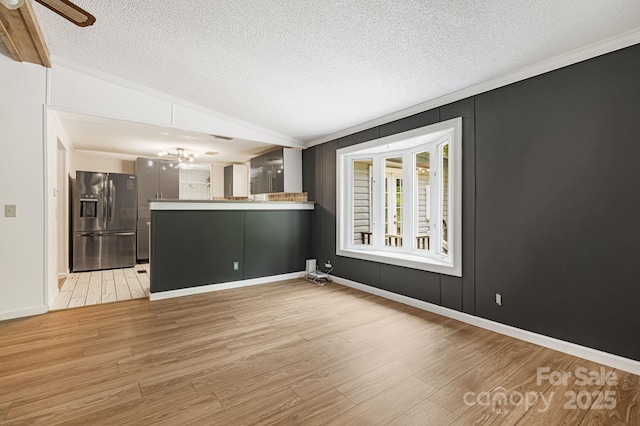 311 Flynn Br, Madison, NC 28753 - unfurnished living room featuring a textured ceiling, crown molding, light wood-style flooring, ceiling fan, and a chandelier