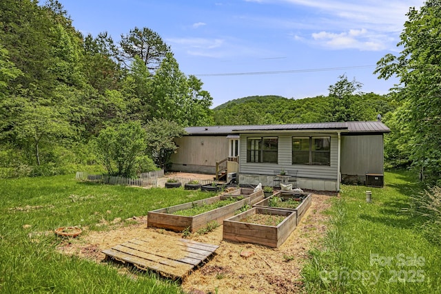 311 Flynn Br, Madison, NC 28753 - back of house featuring a garden, a metal roof, a yard, and a view of trees