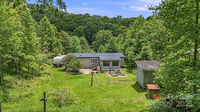 311 Flynn Br, Madison, NC 28753 - rear view of house featuring a wooded view, a yard, and a metal roof