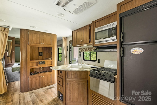 311 Flynn Br, Madison, NC 28753 - kitchen with appliances with stainless steel finishes, light wood-type flooring, light stone countertops, and brown cabinetry