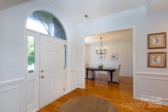 6507 Fairway Point Dr, Charlotte, NC 28269 - foyer featuring crown molding, a chandelier, wood finished floors, wainscoting, and a decorative wall