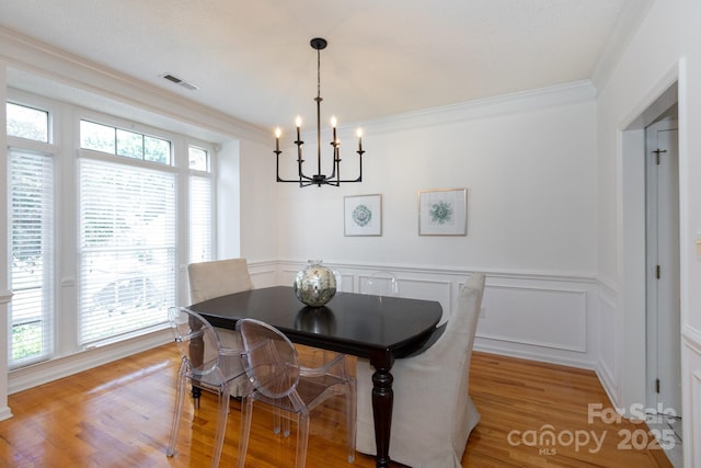 6507 Fairway Point Dr, Charlotte, NC 28269 - dining room featuring a chandelier, light wood-type flooring, wainscoting, a decorative wall, and ornamental molding