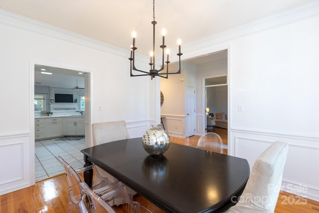 6507 Fairway Point Dr, Charlotte, NC 28269 - dining area with a chandelier, ornamental molding, a decorative wall, wainscoting, and light wood-type flooring