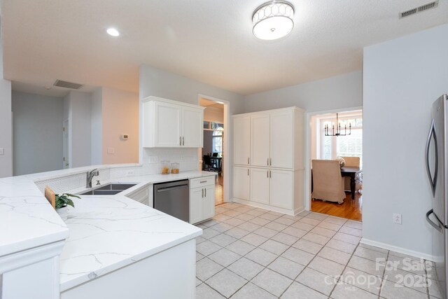 6507 Fairway Point Dr, Charlotte, NC 28269 - kitchen featuring stainless steel appliances, a chandelier, light stone countertops, white cabinetry, and a peninsula