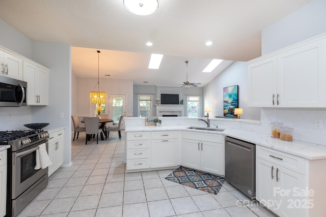 6507 Fairway Point Dr, Charlotte, NC 28269 - kitchen with stainless steel appliances, tasteful backsplash, a peninsula, a skylight, and white cabinets